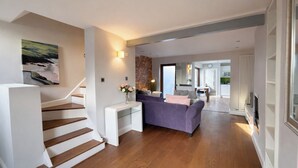 A modern interior with a staircase, a sofa, a dining area, and a kitchen. - Contemporary 2BDR City Retreat (Dublin)