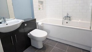A modern bathroom with a white sink, toilet, and bathtub. - Contemporary 2BDR City Retreat (Dublin)