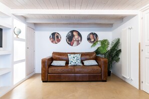 A brown leather sofa with patterned pillows, a globe on a shelf, and three circular artworks on the wall.