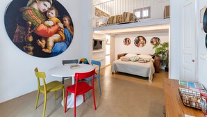 Ein modernes Interieur mit Essbereich, Schlafzimmer im Erker und einem großen Gemälde an der Wand.
