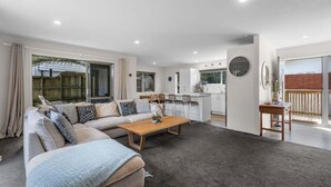 Un salon moderne avec un canapé, une table basse et un coin cuisine à l’arrière-plan.