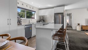 Une cuisine moderne avec des meubles blancs, un îlot central et une vue sur l’extérieur.