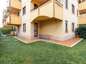 Un edificio residencial de varios pisos con balcones, un pequeño patio y un césped bien cuidado.