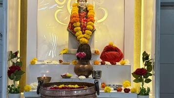 A shrine with a statue, flowers, and a brass bowl.