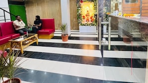 A hotel lobby with a reception desk, a red sofa, and a decorative floral arrangement.