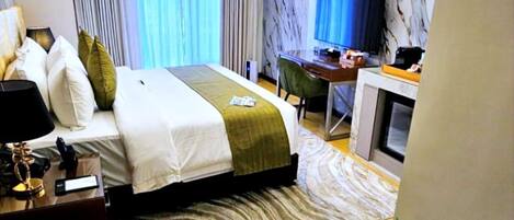 Habitación de hotel con cama, escritorio y ventilador de techo.