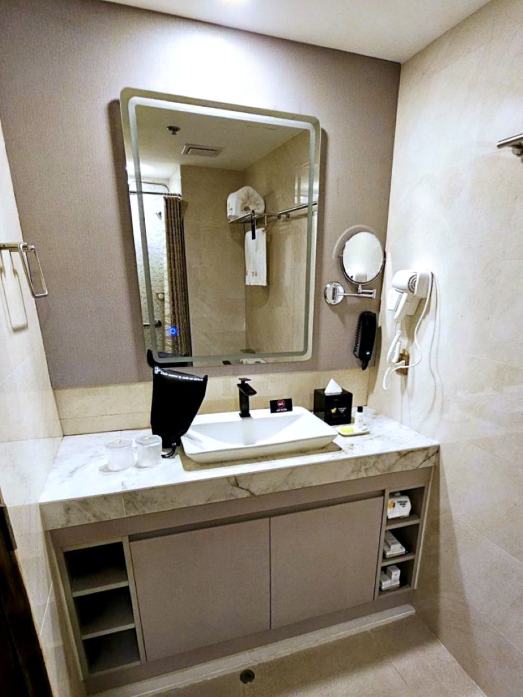 Une salle de bain moderne équipée d’un grand miroir, d’un lavabo, d’un sèche-cheveux et d’un téléphone.