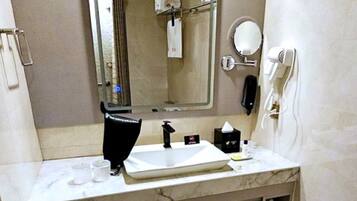 Une salle de bain moderne équipée d’un grand miroir, d’un lavabo, d’un sèche-cheveux et d’un téléphone.