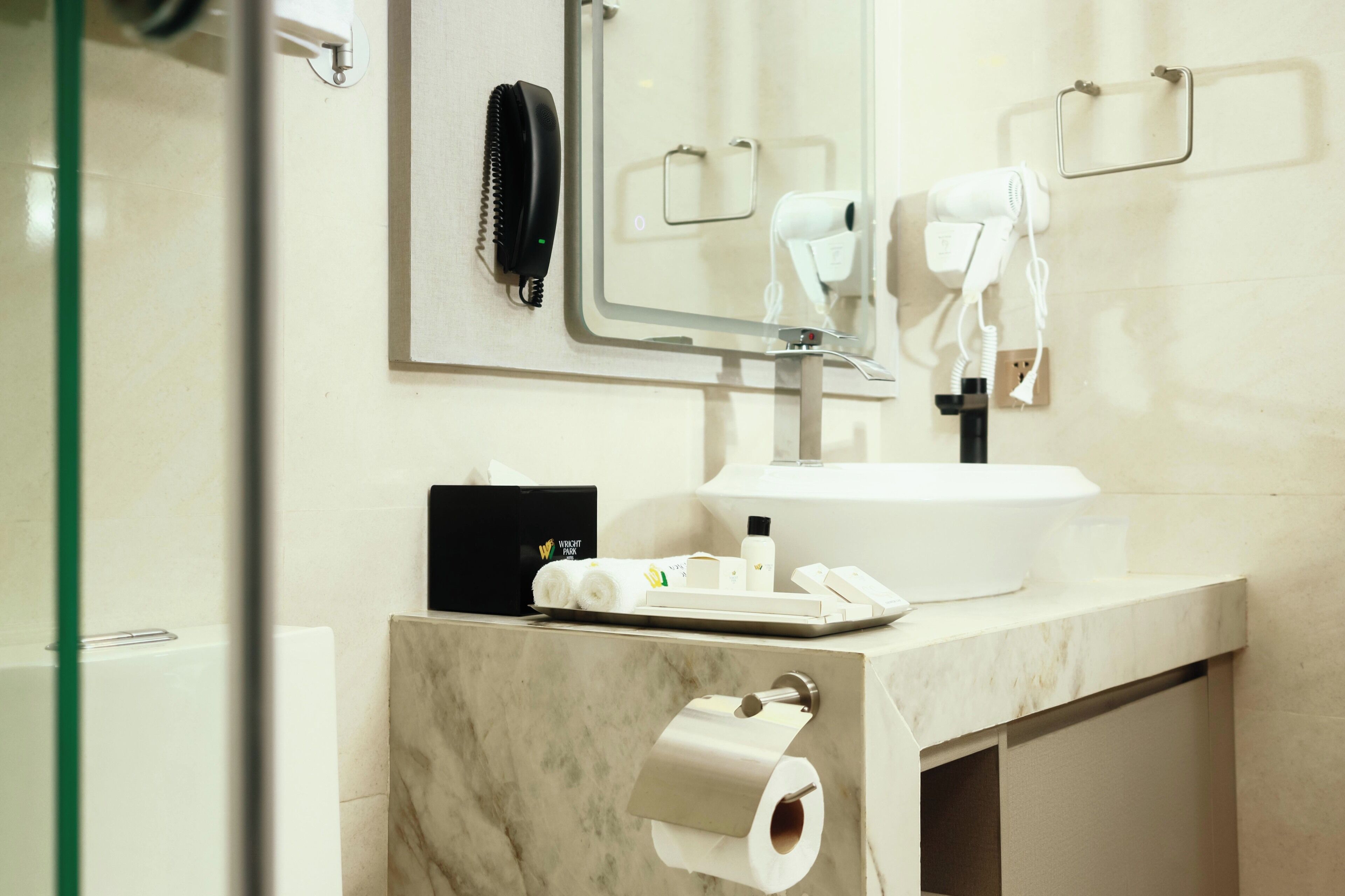 Un baño con lavamanos de mármol, un espejo, un secador de pelo y un teléfono.