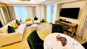 A modern hotel room with a living area, dining table, and a flat-screen TV. - Wright Park Hotel (Baguio)
