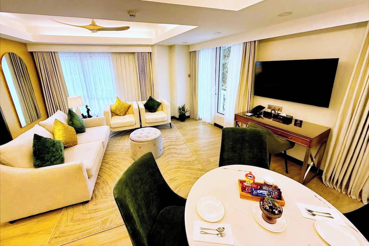 Ein modernes Hotelzimmer mit Wohnbereich, Esstisch und Flachbildfernseher.