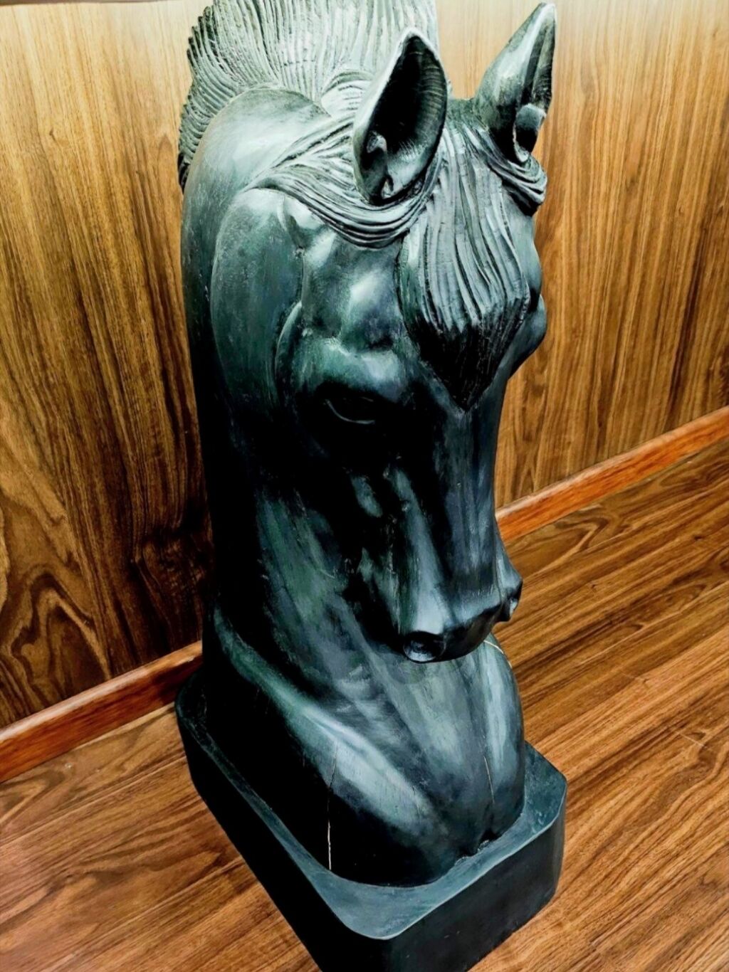 A sculpture of a horse's head mounted on a dark base.