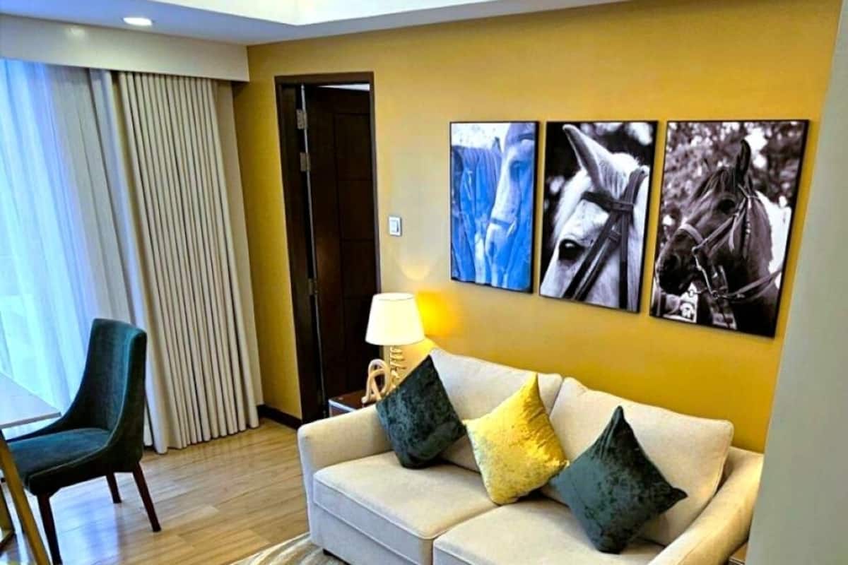 Ein modernes Wohnzimmer mit Sofa, Hocker und Kunstwerk an der Wand.
