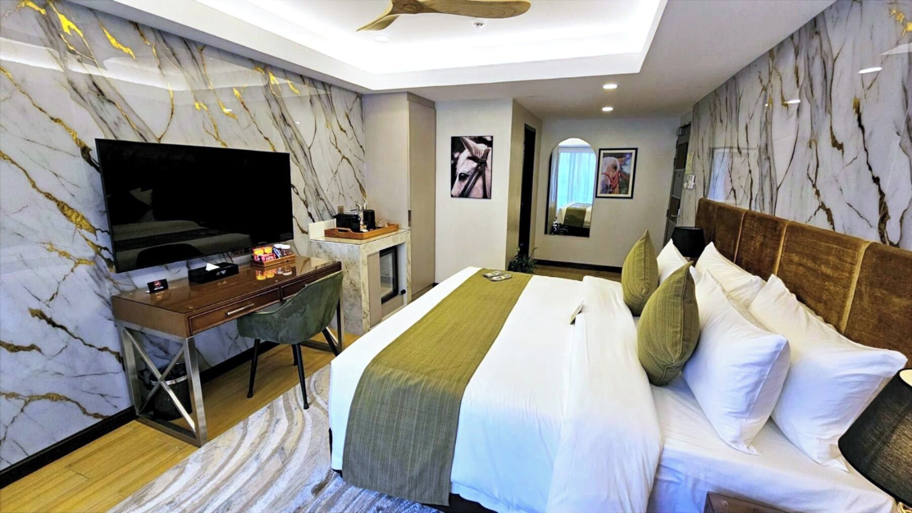 A hotel room with a bed, desk, TV, and a ceiling fan.