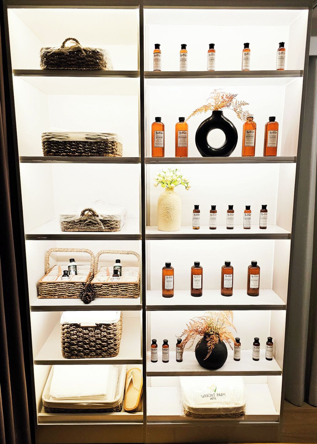 A display of various items including woven baskets, a vase with flowers, and bottles of products on shelves.
