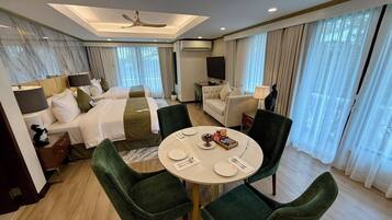 Una habitación de hotel con dos camas, una mesa de comedor con sillas, un sofá y un ventilador de techo.