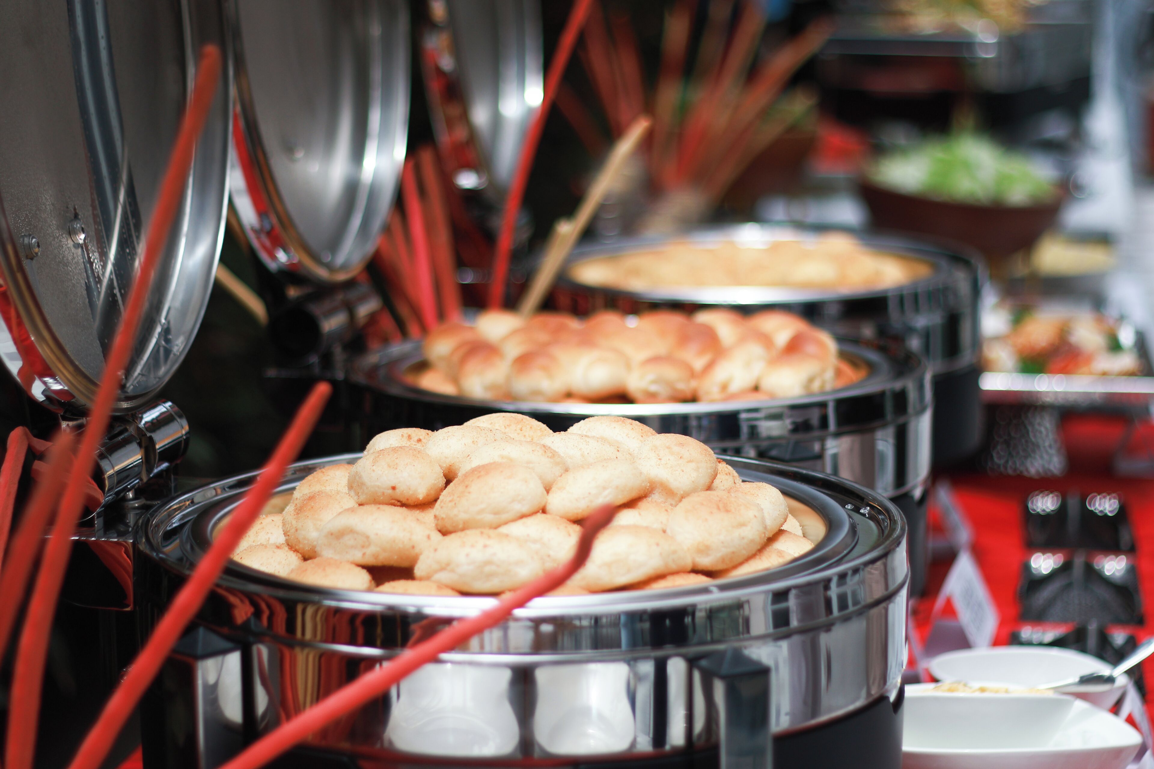 A buffet with multiple serving stations, each with a metal container and a ladle.