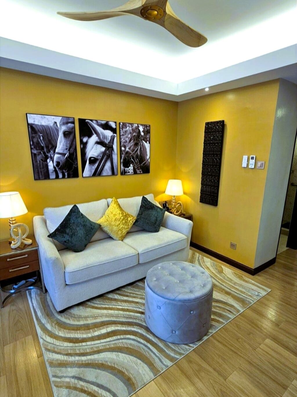 A modern living room with a sofa, ottoman, and artwork on the wall.