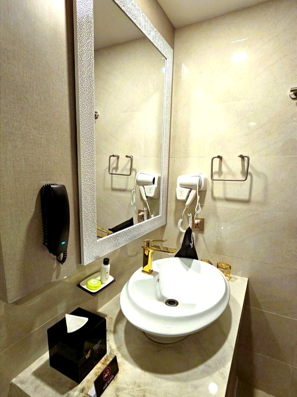 A modern bathroom with a large mirror, a white sink, and two towel racks.