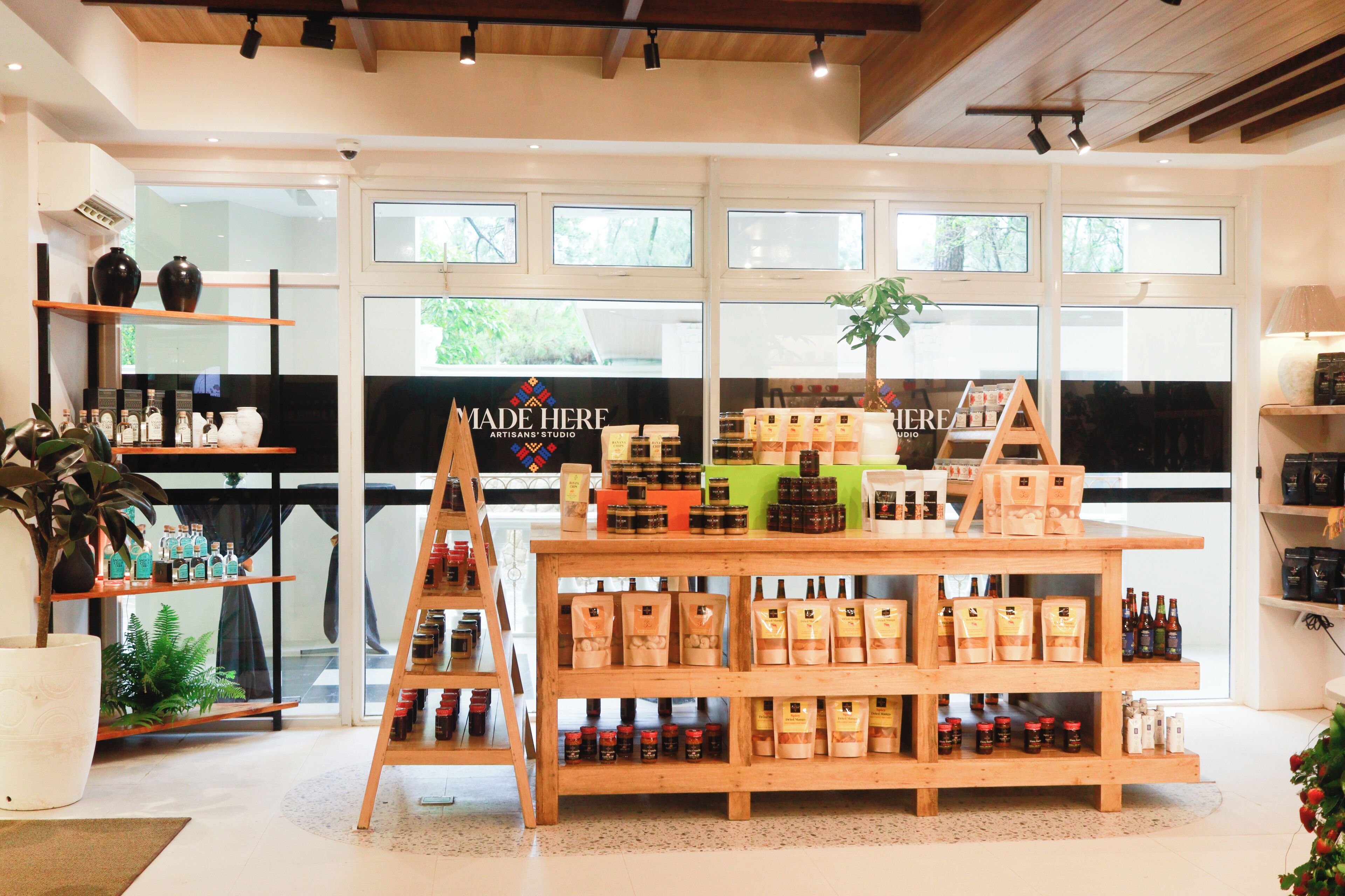 Een goed verlichte winkel met houten schappen vol diverse producten, een centraal presentatietafel en grote ramen die natuurlijk licht binnenlaten.