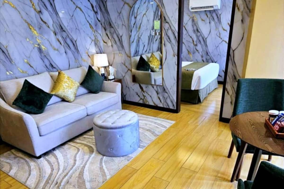 Ein modernes Wohnzimmer mit einer Couch, einem Hocker und einem Esstisch mit Stühlen.