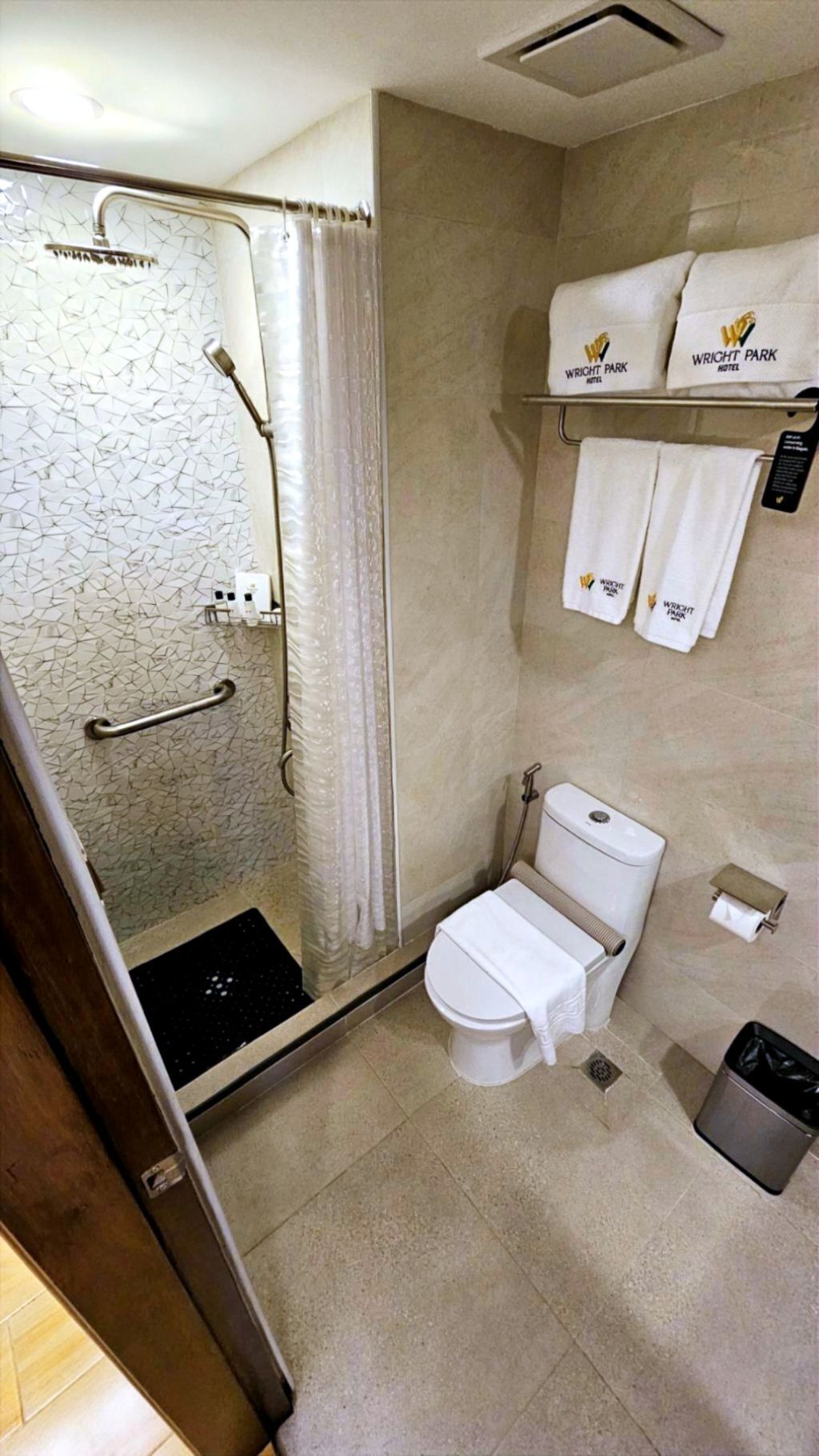 A bathroom with a shower, toilet, and towel rack.