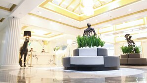 A hotel lobby with a reception desk, a black horse statue, a round seating area, and a ceiling with a skylight. - Wright Park Hotel (Baguio)