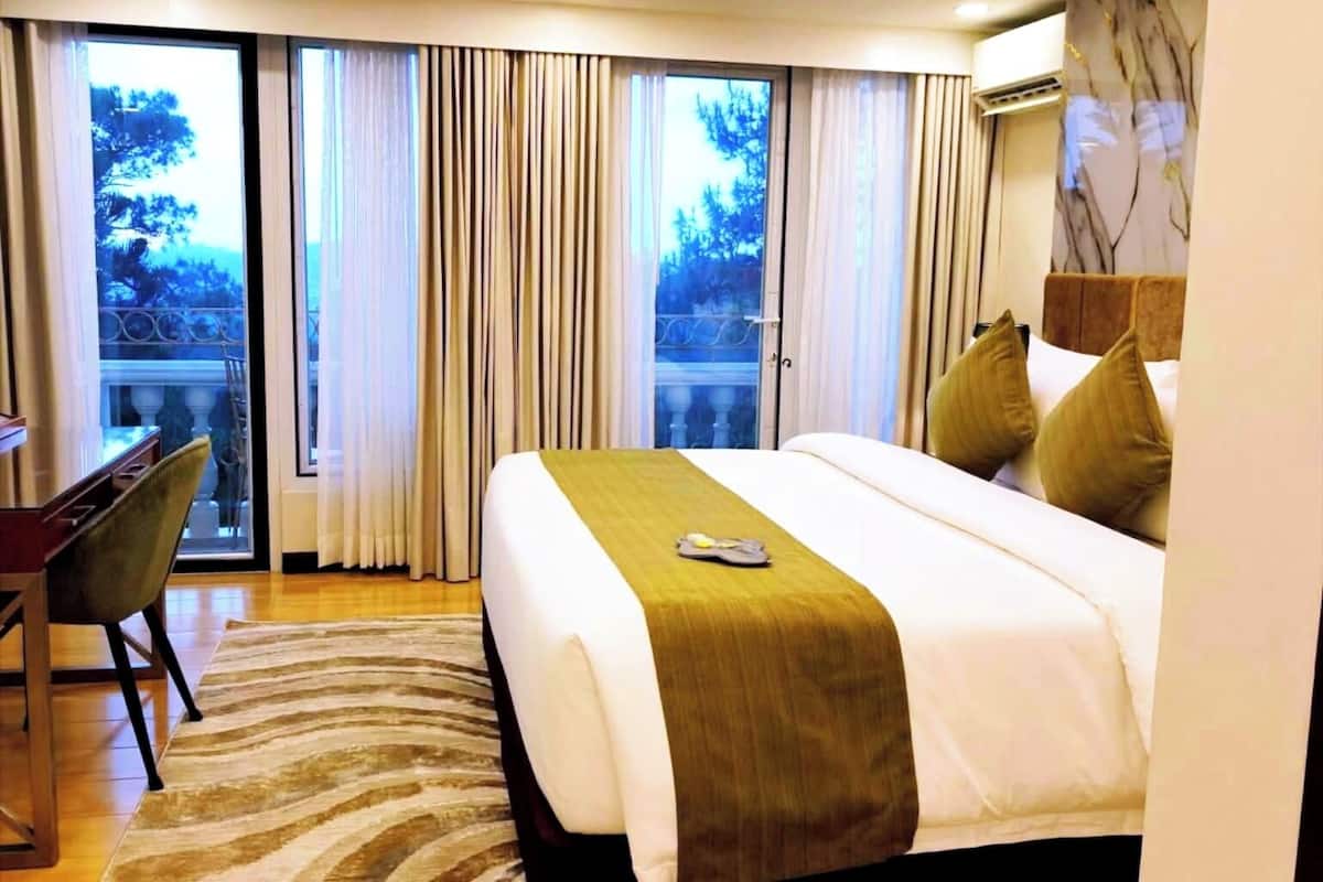Ein modernes Hotelzimmer mit einem großen Bett, einem Schreibtisch und Blick ins Freie.