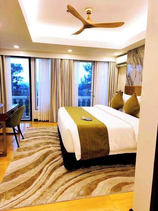 A modern hotel room with a large bed, a desk, and a view of the outdoors. - Wright Park Hotel (Baguio)