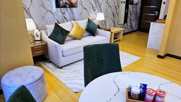 A modern living room with a white sofa, green and yellow cushions, a round marble table, and a ceiling fan.