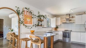 Een moderne keuken met witte kastjes, een roestvrijstalen oven en een houten kookeiland met barkrukken.