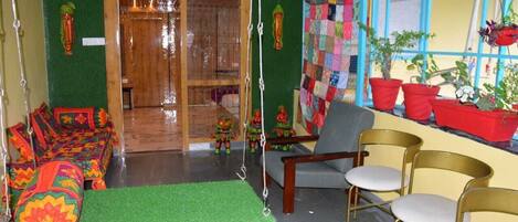 A room with a green carpet, a wooden door, a colorful quilt, and red planters.