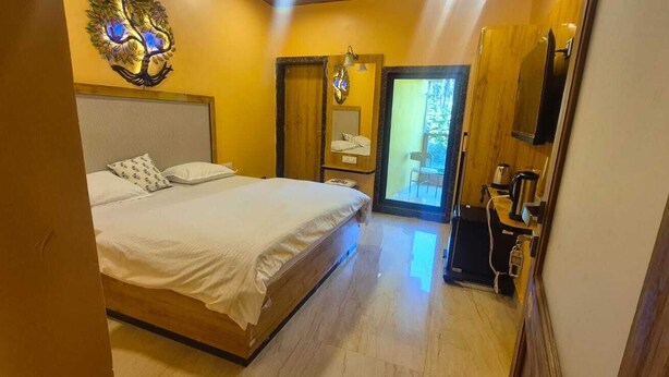 A bedroom with a bed, a wooden headboard, a nightstand, a mirror, and a door leading to a balcony.