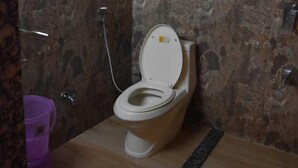 A bathroom with a toilet, a shower, and a small window.