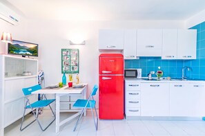 Eine moderne Küche mit weißen Schränken, einem roten Kühlschrank und einer blauen gefliesten Spritzschutzwand.