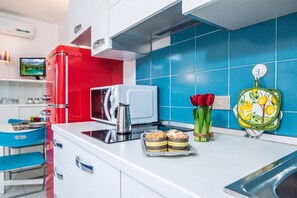 Une cuisine moderne avec un réfrigérateur rouge, un four à micro-ondes blanc et un dosseret de carrelage bleu.