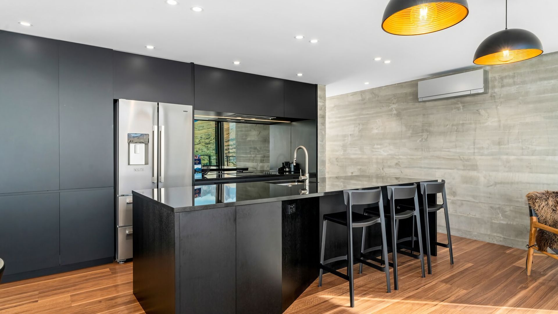 A modern kitchen with a central island, stainless steel appliances, and a bar area with chairs.