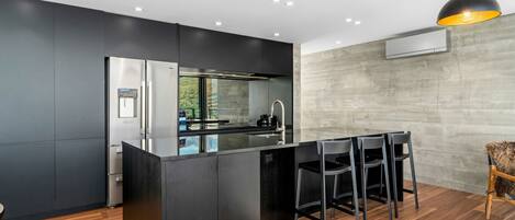 A modern kitchen with a central island, stainless steel appliances, and a bar area with chairs.