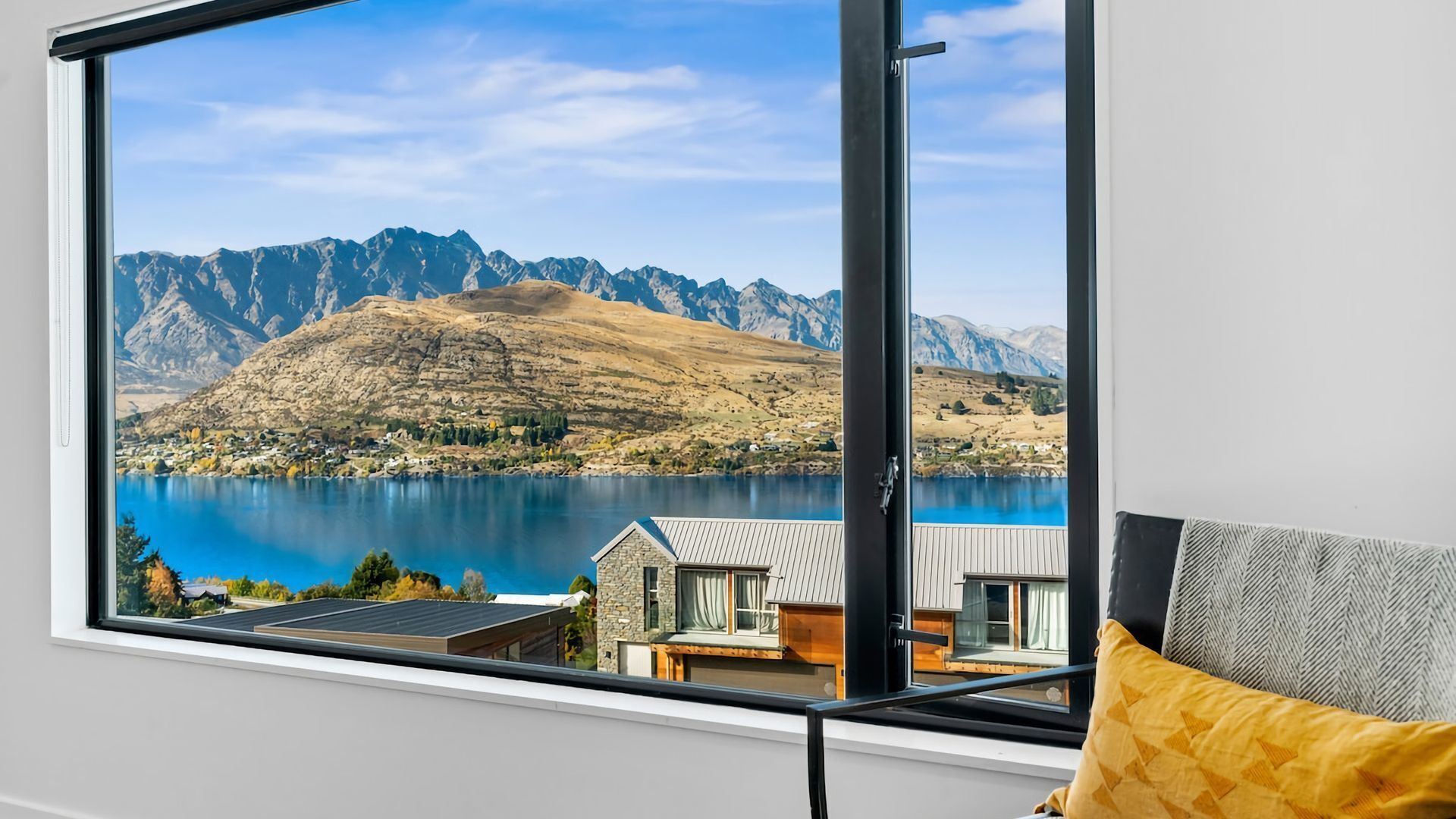 A room with a large window offering a view of a lake and mountains.