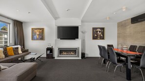 Ein modernes Wohnzimmer mit Kamin, Flachbildfernseher und Kunstwerken an den Wänden.