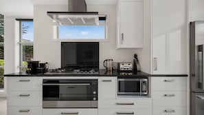 Une cuisine moderne équipée d’une cuisinière à gaz, d’un four à micro-ondes et d’un four encastré.