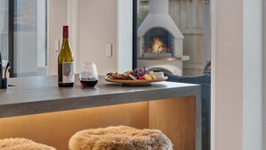 A modern kitchen with a wine bottle, glasses, and a fruit platter on the counter. - Central Queenstown Villa Spa (Queenstown)