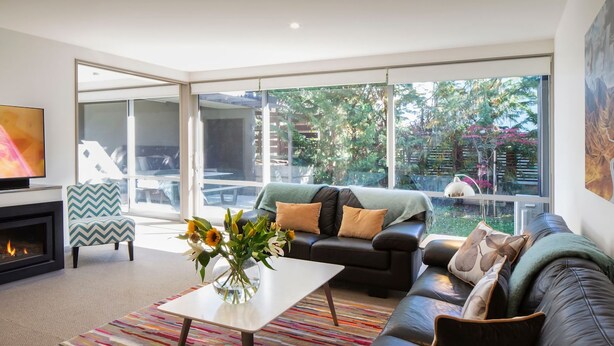 A modern living room with a fireplace, a sofa, a coffee table, and a TV. - Apartment G3 3BR Near Queenstown Centre (Queenstown)
