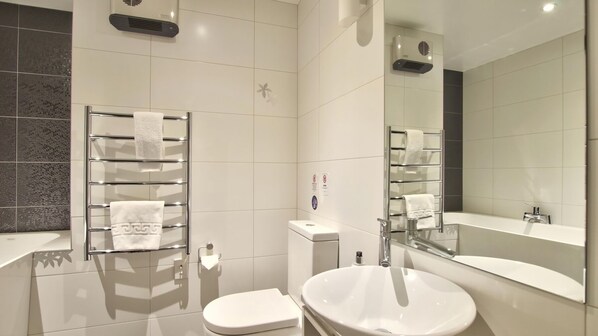 Ein modernes Badezimmer mit Toilette, Waschbecken und einem großen Spiegel.