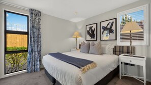 A hotel room with a large bed, a nightstand, a lamp, and artwork on the wall. - Central Queenstown 3 Bed Villa (Queenstown)