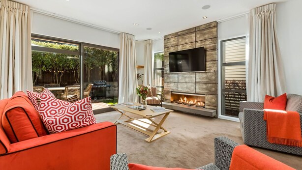 A modern living room with a fireplace, comfortable seating, and large windows. - Central Queenstown 3 Bed Villa (Queenstown)