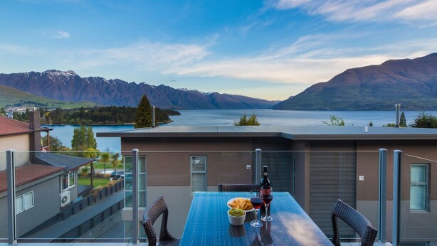 Een modern gebouw met een balkon met uitzicht op een meer en bergen.