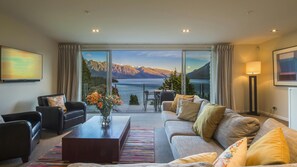 Un salon spacieux doté d’une grande fenêtre offrant une vue panoramique sur les montagnes et le lac.