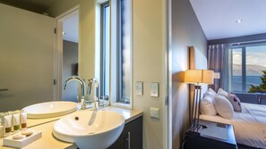 A hotel room with two sinks, a bed, a lamp, and a window with a view. - LakeRidge Queenstown Front Row (Queenstown)