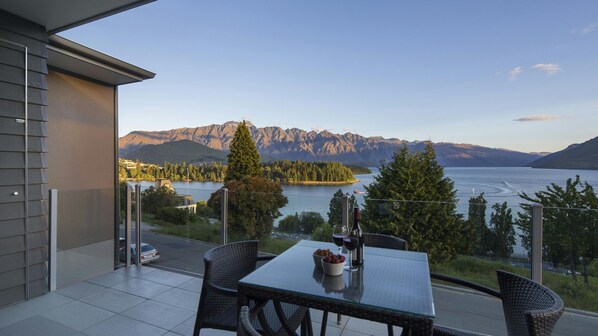 A balcony with a table, chairs, and a view of a lake and mountains. - LakeRidge Queenstown Front Row (Queenstown)